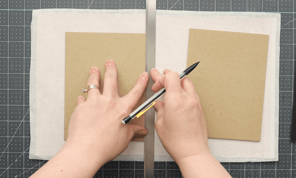 hands holding cover boards showing how to trace the outline on covering material in order to make a case for the casebinding