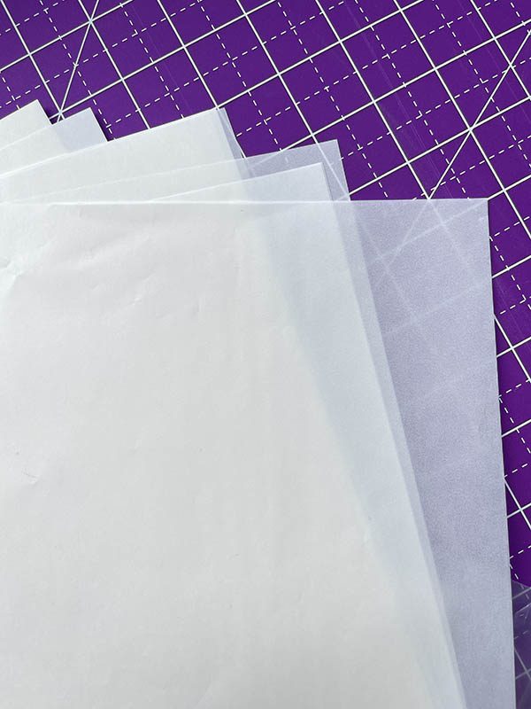 white transparent vellum glassine sheets on purple backdrop