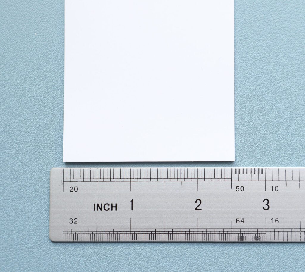 white paper on a blue backdrop with a ruler showing a width of 2 and a half inches