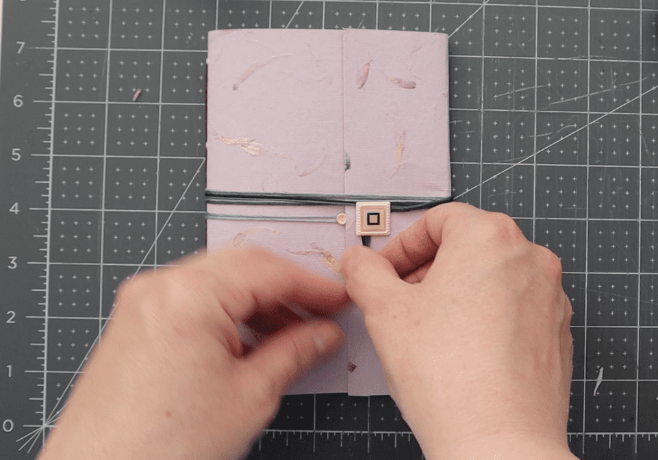 three photos showing stages of the closure creation process, including measuring the closure opening with a ruler, attaching a button brad to hold thread in place and wrapping the pamphlet as a last step