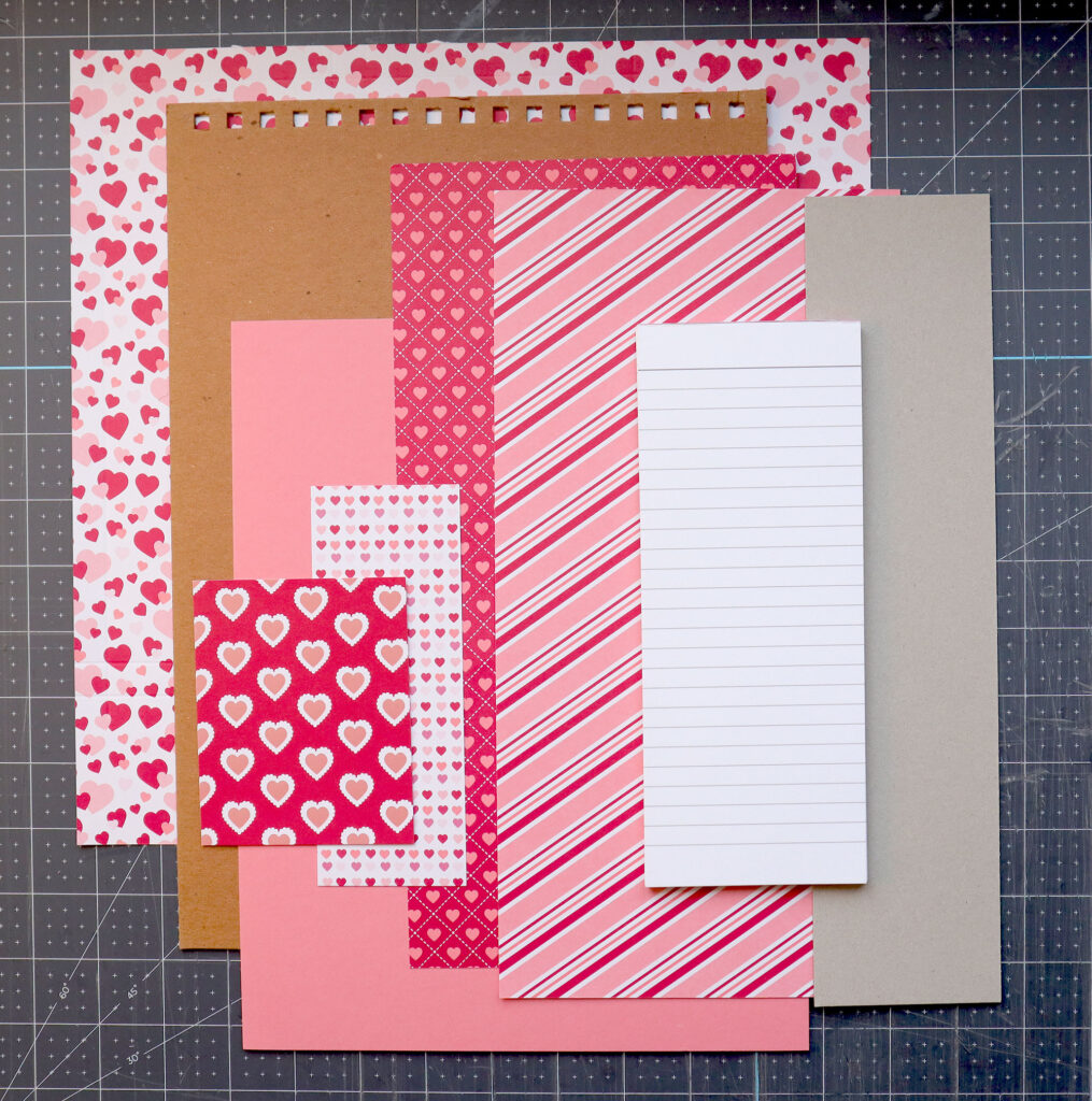 various materials needed to make a handmade love notes pad, including 12x12 stampin up from my heart specialty decorative card stock, construction paper