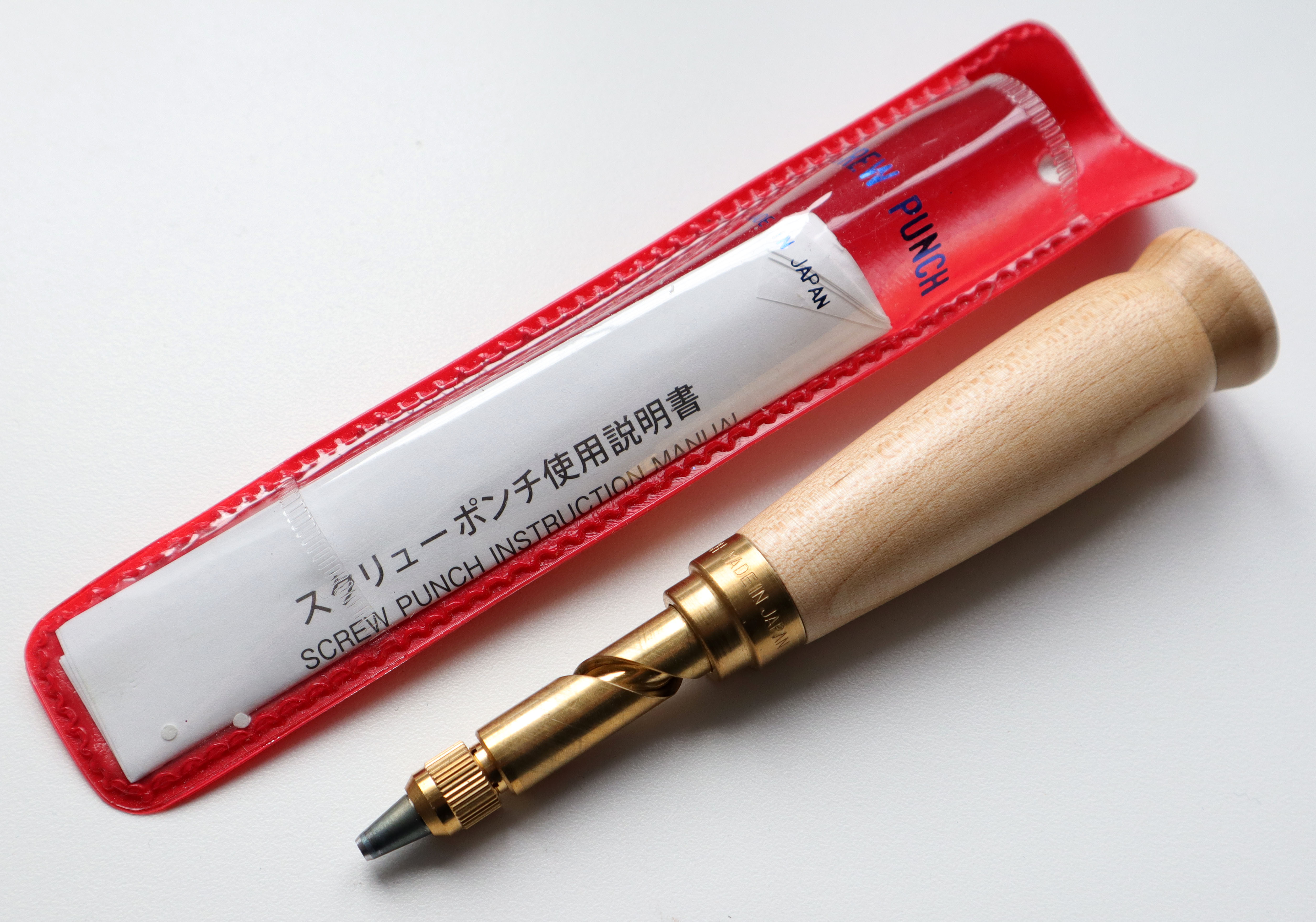 a japanese screw punch made in japan with red sleeve and instructions in japanese writing