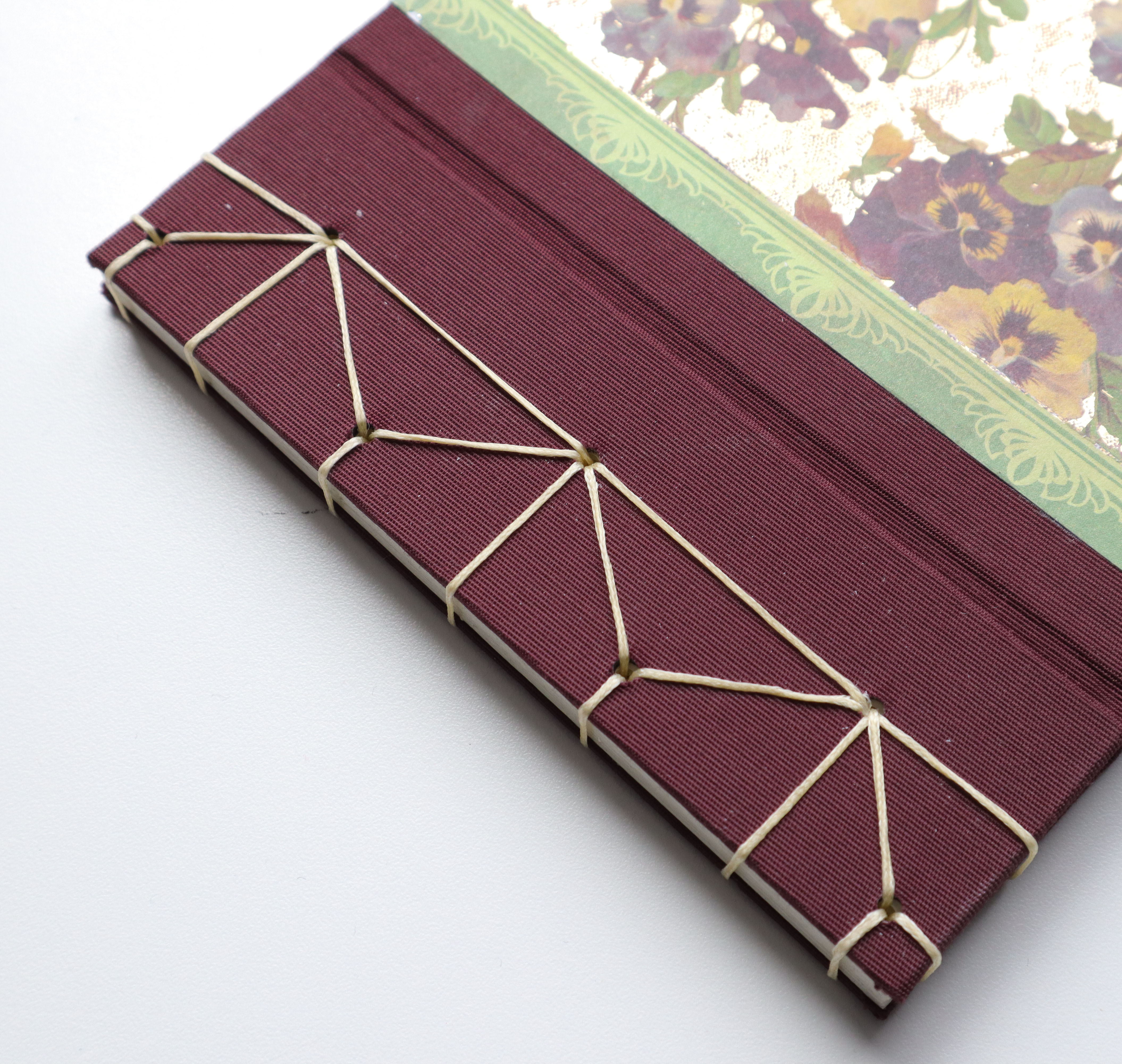 a book with burgundy book cloth and a floral cover sewn by misty mcintosh featuring the hemp leaf japanese stab binding technique