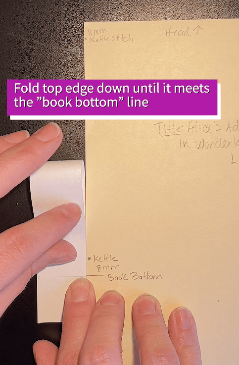 Hold the text paper in position and fold down the top edge until it meets the "book bottom" line.