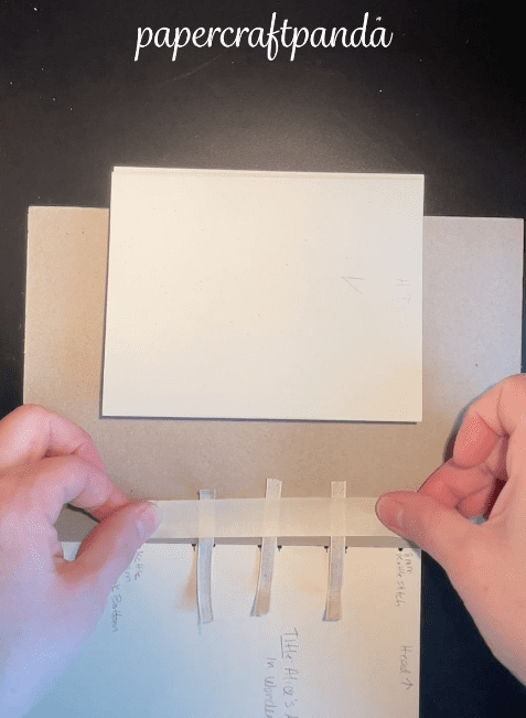 showing step 4 of how to make a bookbinding sewing frame using leftover book board and tape