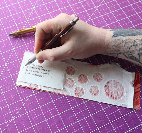 measuring for hole placement on the layered weathergram pieces on a purple self healing cutting mat